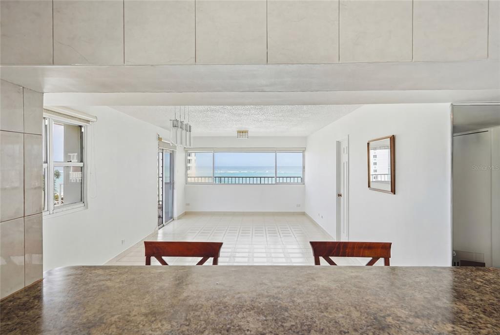 A view from a kitchen counter looking into an open living area with ocean views — 1477 Ave Ashford TORRE DEL MAR UNIT 801, SAN JUAN, PR