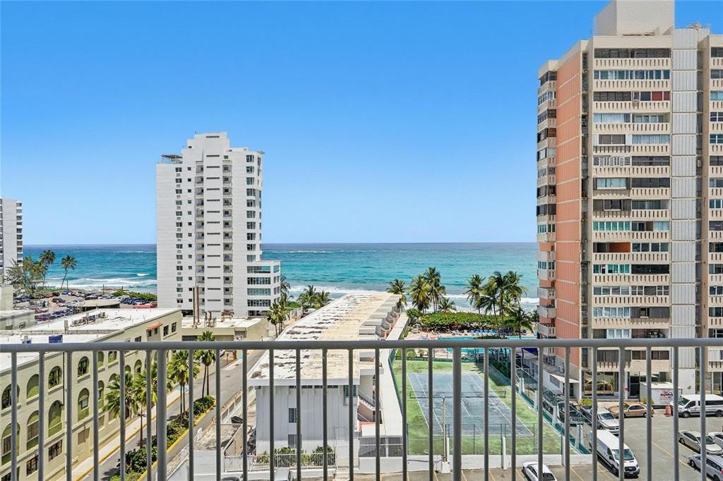 A view from a balcony overlooking a tennis court, parking lot, and the ocean — 1477 Ave Ashford TORRE DEL MAR UNIT 801, SAN JUAN, PR