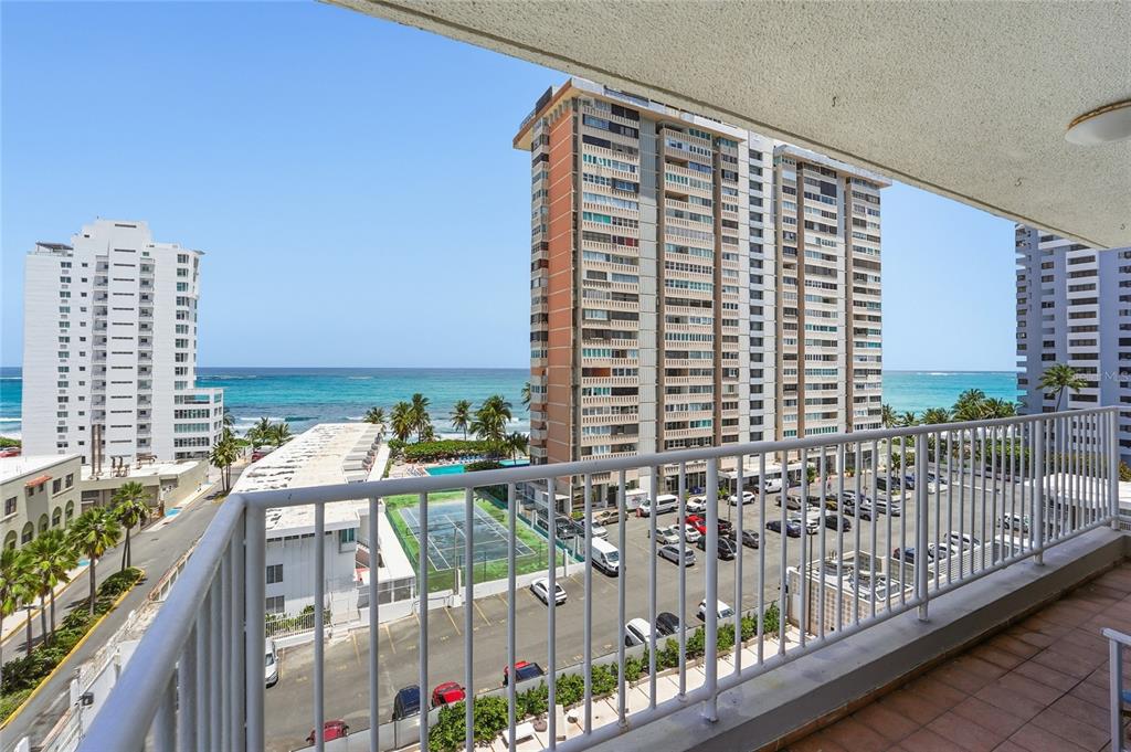 A balcony view overlooking a parking lot, a tennis court, and the ocean — 1477 Ave Ashford TORRE DEL MAR UNIT 801, SAN JUAN, PR