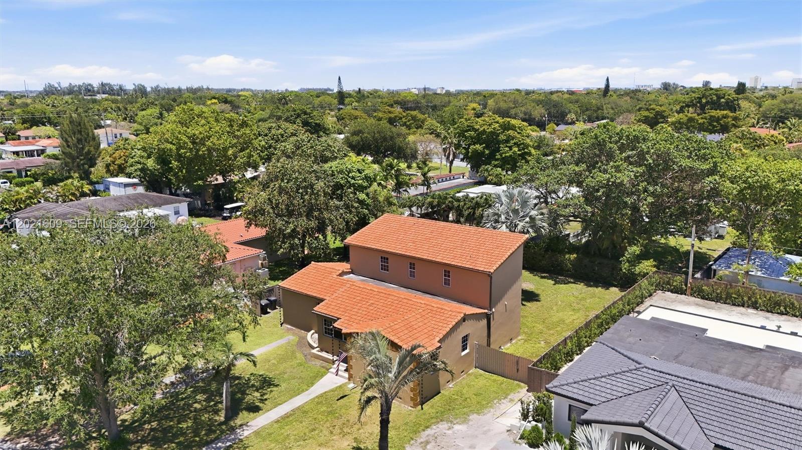An aerial view shows a two-story house with a red tile roof and surrounding trees — 245 Lenape Dr, Miami Springs FL 33166, MIAMI SPRINGS, FL