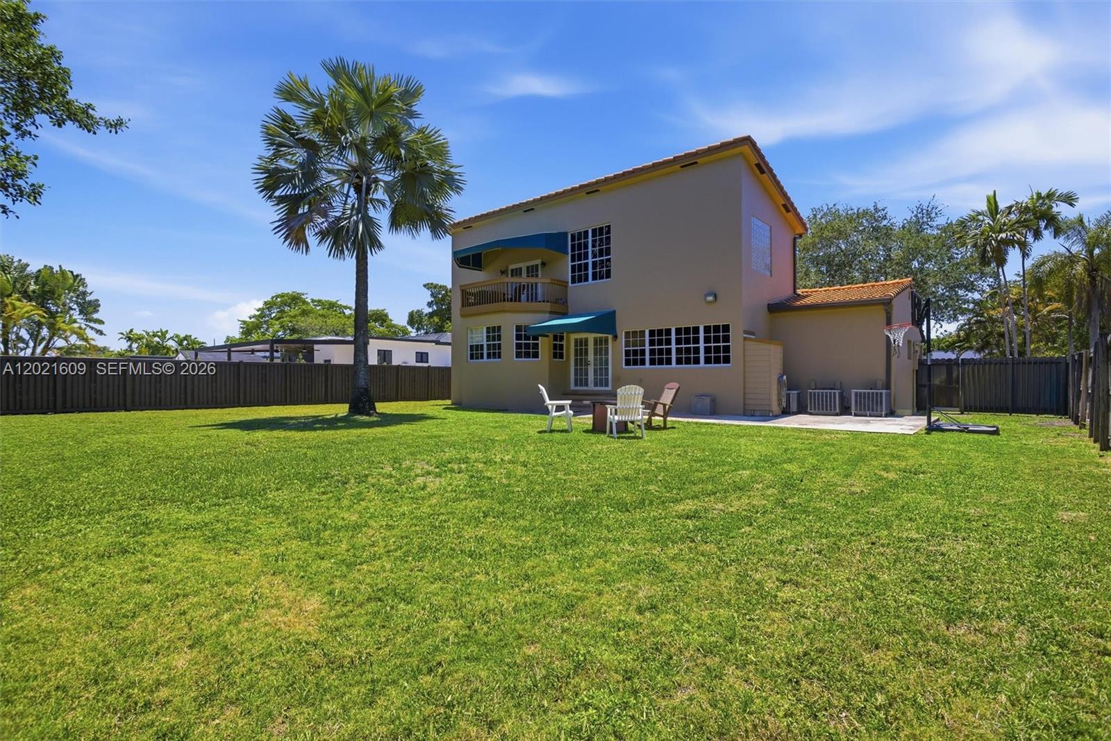 The exterior of a two-story house features a large grassy backyard and a palm tree — 245 Lenape Dr, Miami Springs FL 33166, MIAMI SPRINGS, FL