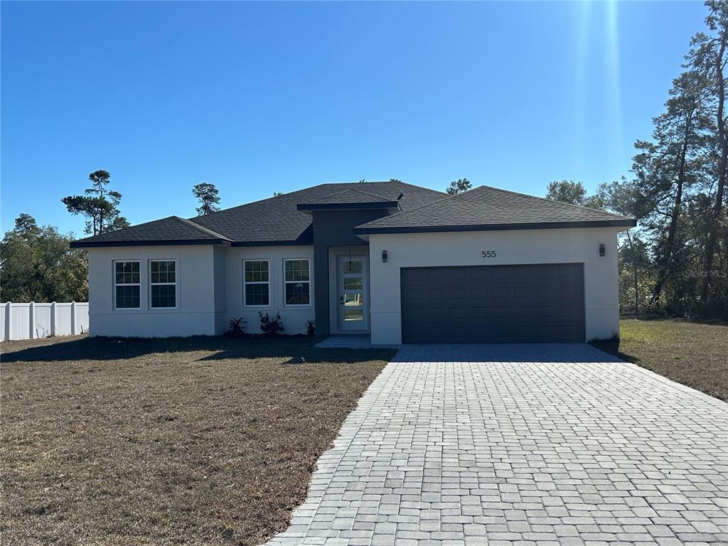 A single-story house with a light-colored exterior, dark roof, and a paved driveway — 555 MARION OAKS GOLF ROAD, OCALA, FL