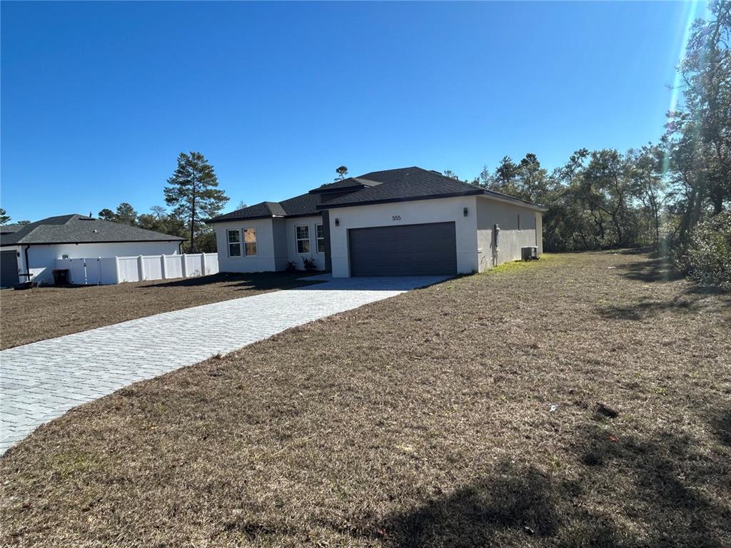 A single-story house with a paved driveway and a two-car garage sits on a lot — 555 MARION OAKS GOLF ROAD, OCALA, FL