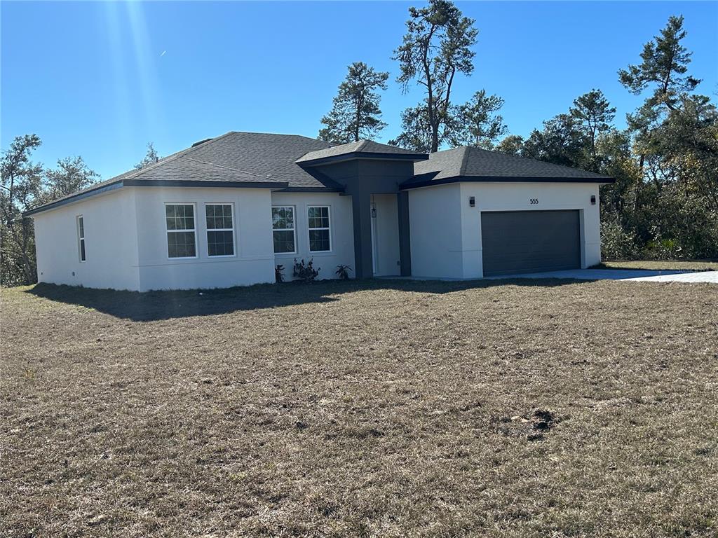 A single-story house with a white stucco exterior and a two-car garage — 555 MARION OAKS GOLF ROAD, OCALA, FL