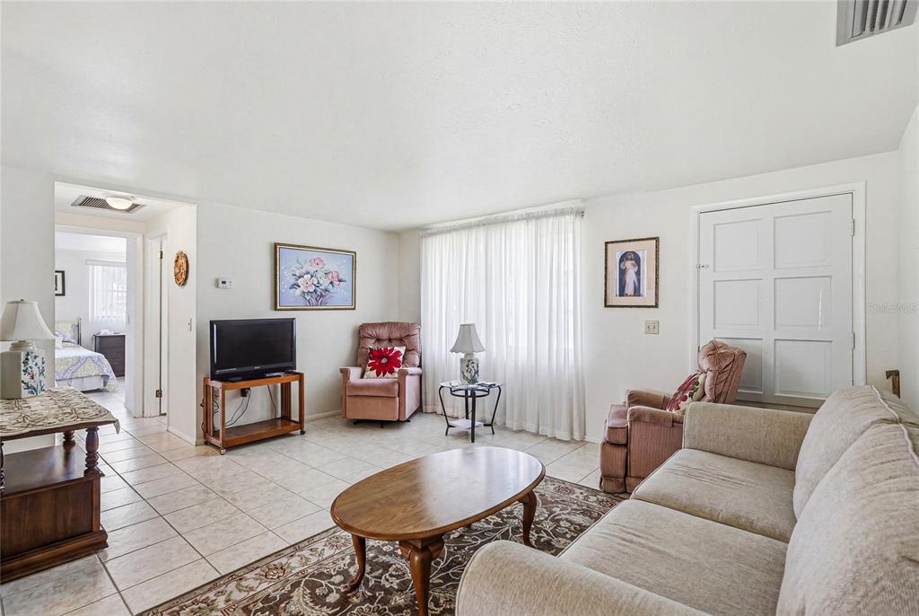 A living room features tile flooring, a beige sofa, two armchairs, and a television — 300 SAN MARINO AVENUE, NORTH PORT, FL