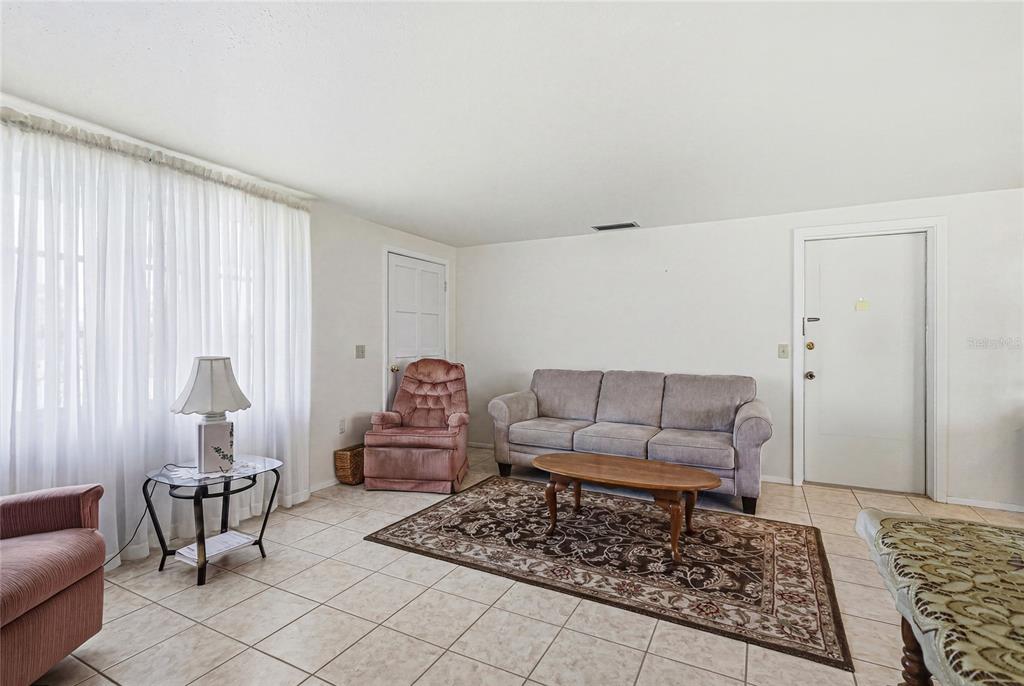 A living room features tile flooring, a gray sofa, a pink armchair, and a rug — 300 SAN MARINO AVENUE, NORTH PORT, FL