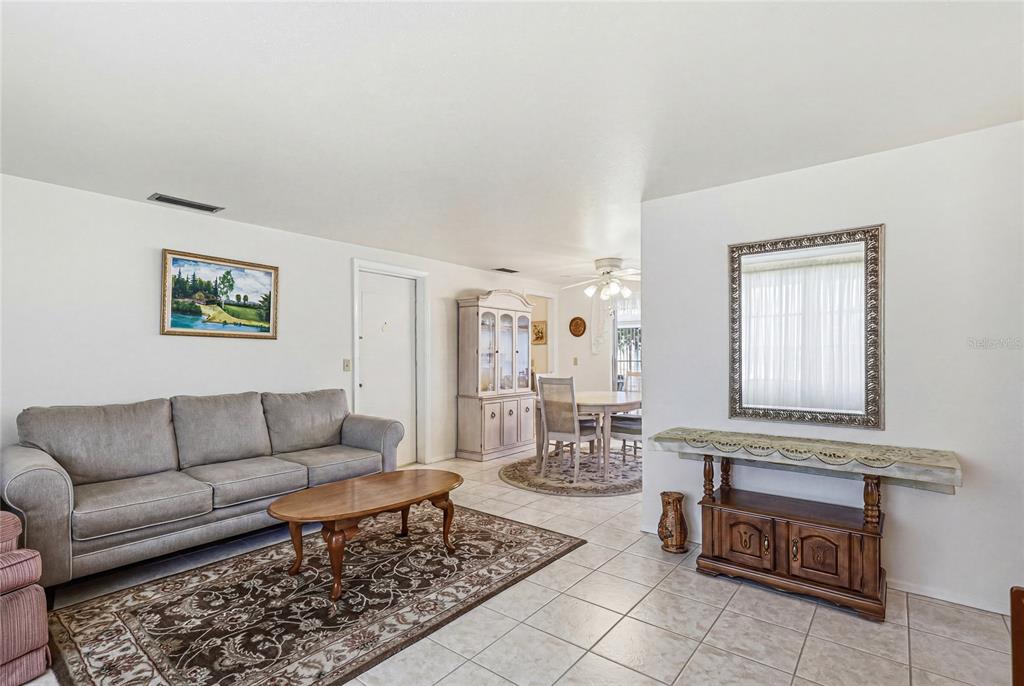 A living room with a gray sofa, coffee table, and a dining area beyond — 300 SAN MARINO AVENUE, NORTH PORT, FL