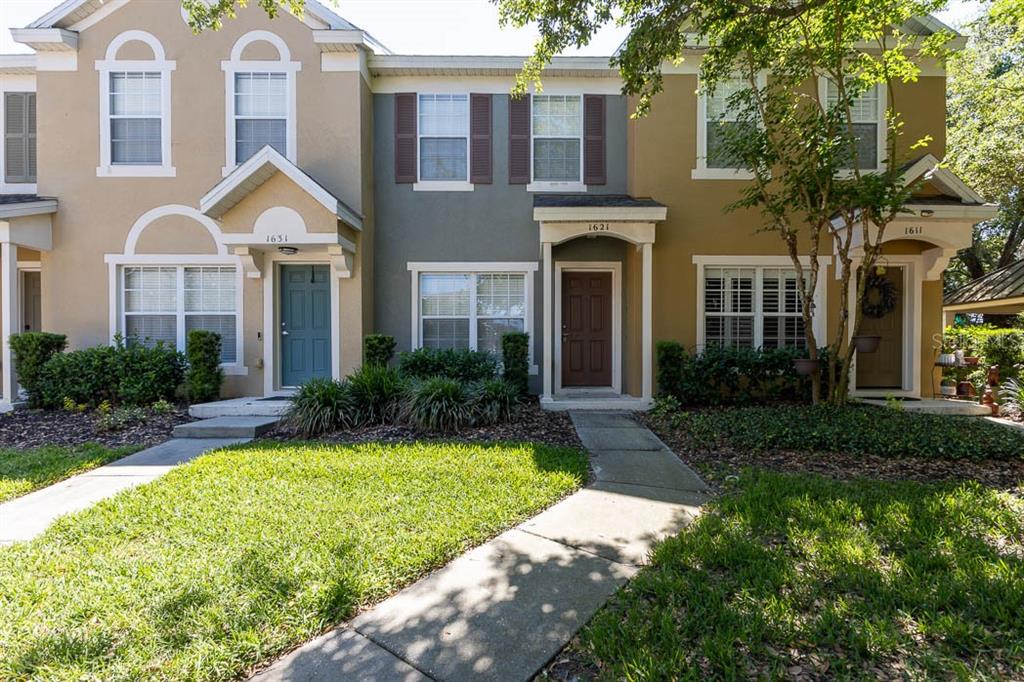 A row of three two-story townhouses with tan and gray siding and front entryways — 1621 STOCKTON DRIVE, SANFORD, FL