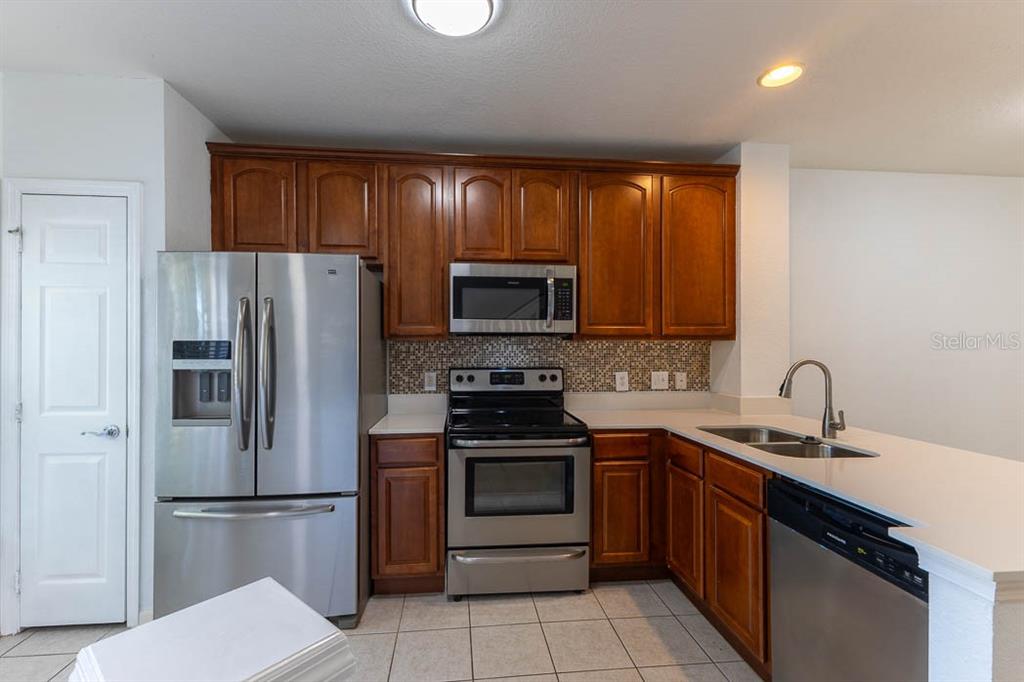 A kitchen features wood cabinets, stainless steel appliances, a tiled backsplash, and white countertops — 1621 STOCKTON DRIVE, SANFORD, FL