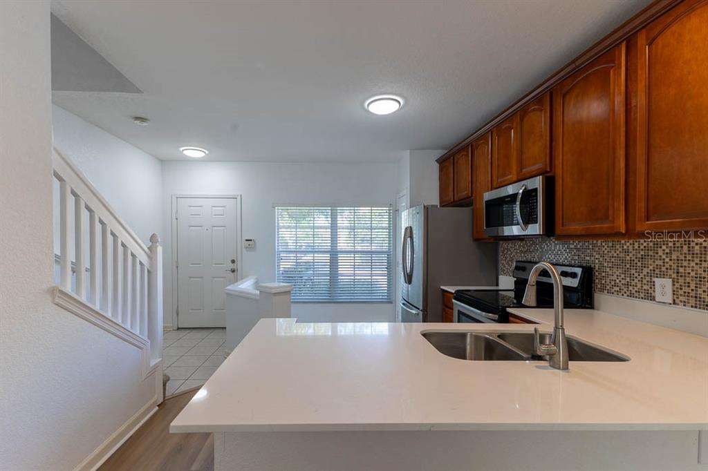 A kitchen with white countertops, wood cabinets, and a view of the entryway and stairs — 1621 STOCKTON DRIVE, SANFORD, FL