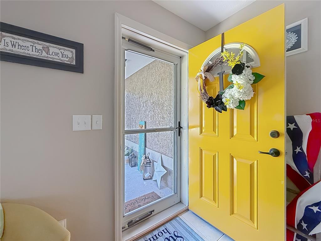 A bright yellow front door with a floral wreath opens to a covered porch — 6050 SW 155TH STREET ROAD, OCALA, FL
