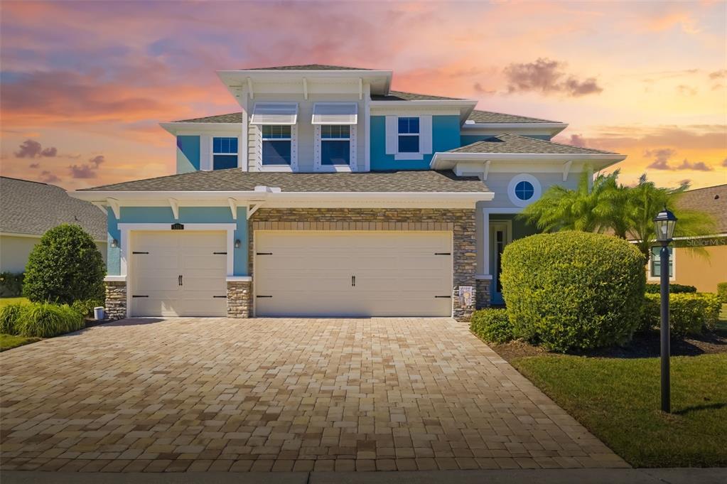 A living room opens through sliding glass doors to a screened patio overlooking a lake — 5315 BENTGRASS WAY, LAKEWOOD RANCH, FL