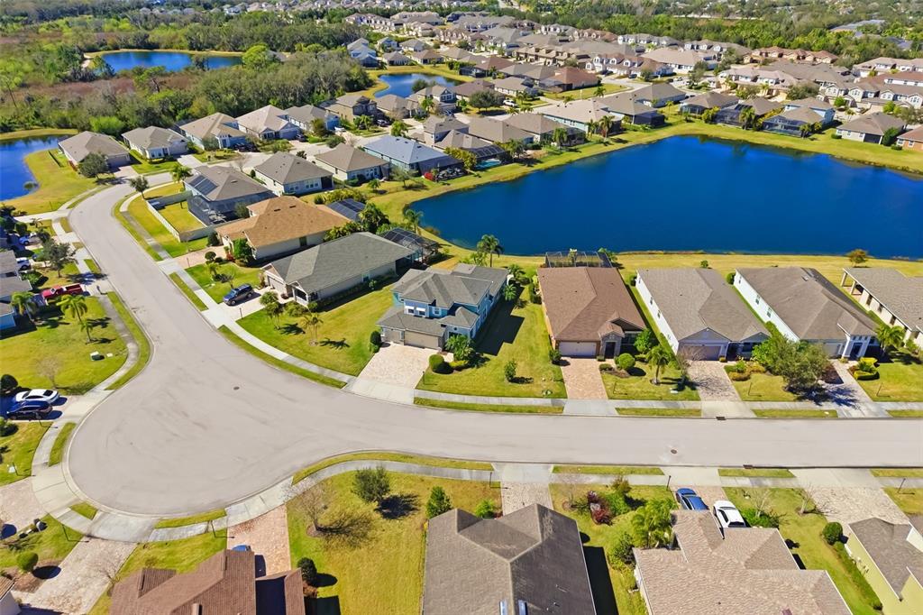 A two-story house with a screened-in patio overlooks a pond at dusk — 5315 BENTGRASS WAY, LAKEWOOD RANCH, FL