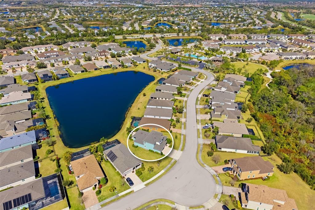 A covered patio with a dining set overlooks an open-concept kitchen and living area — 5315 BENTGRASS WAY, LAKEWOOD RANCH, FL