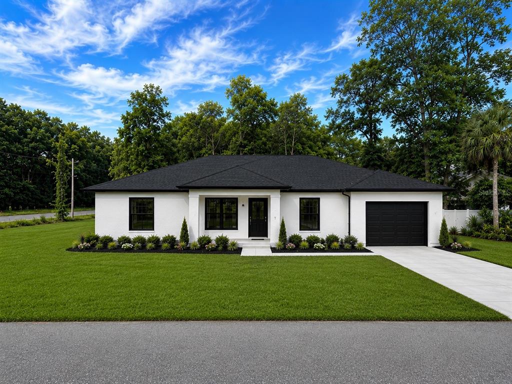 A single-story white house with a black roof and garage sits on a grassy lawn — 11491 NW 92ND CT, CHIEFLAND, FL