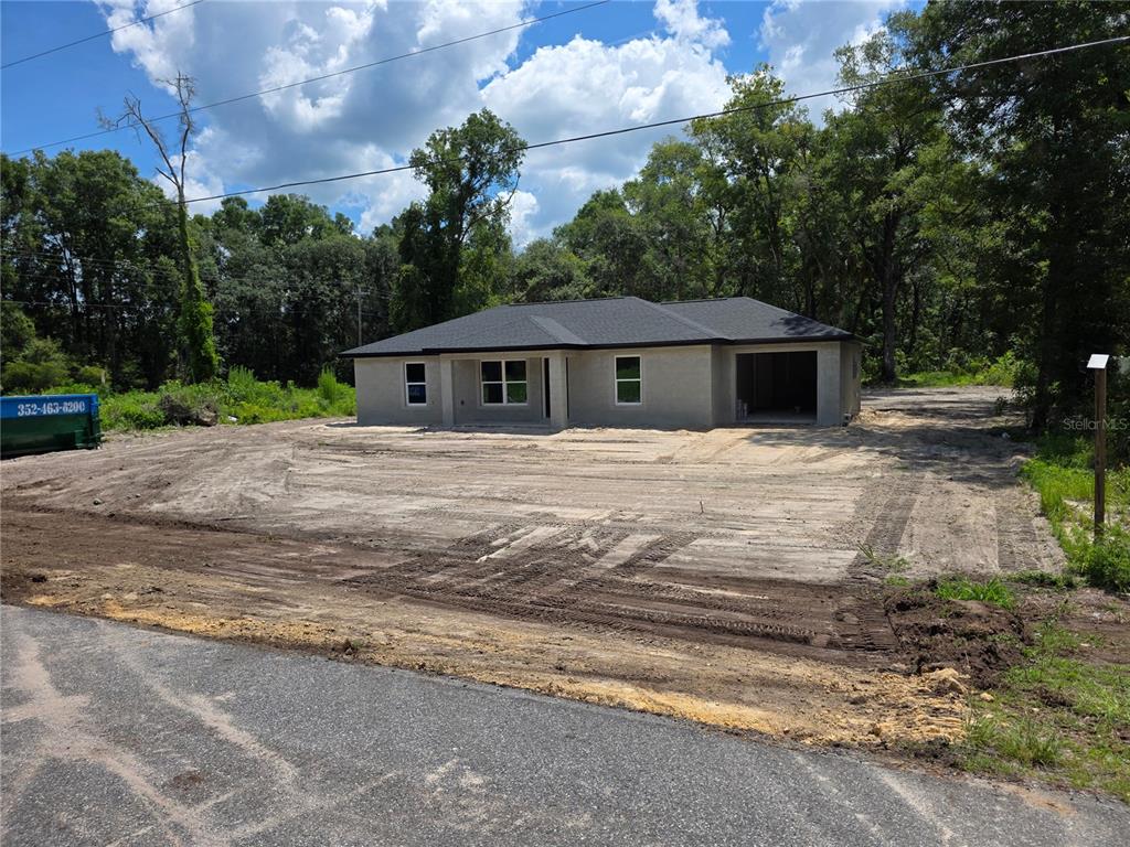 A newly constructed single-story house with a garage sits on a cleared, sandy lot — 11491 NW 92ND CT, CHIEFLAND, FL