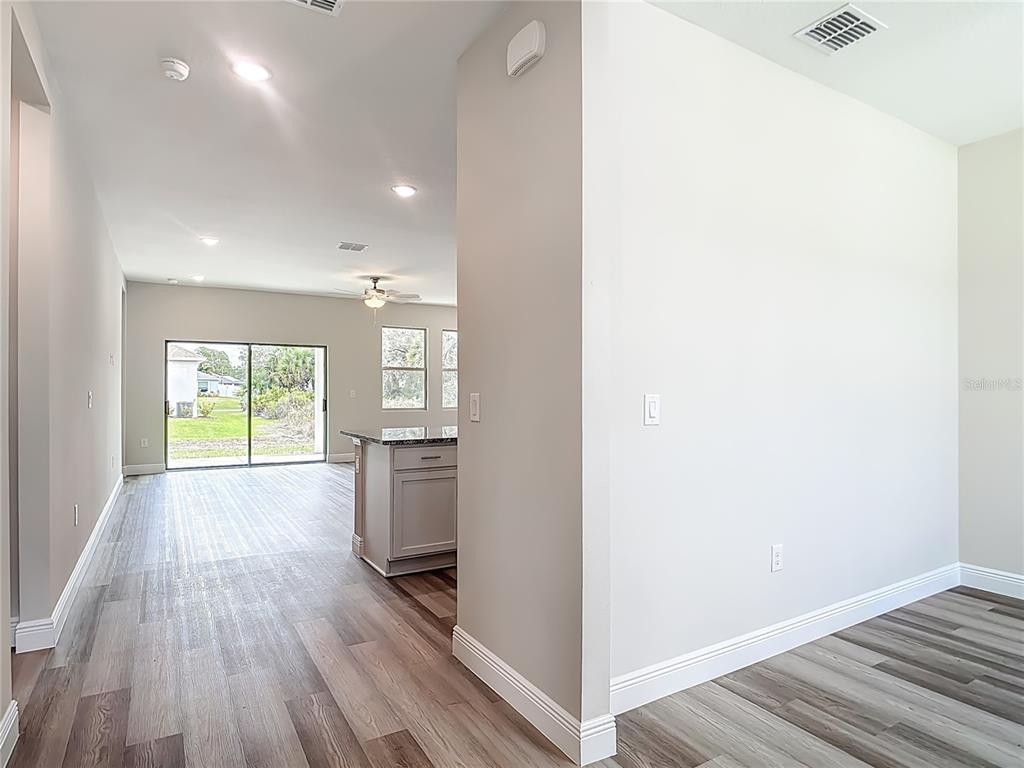 A view from a hallway looking into an open-concept kitchen and living area with flooring — 2021 S CHAMBERLAIN BOULEVARD, NORTH PORT, FL