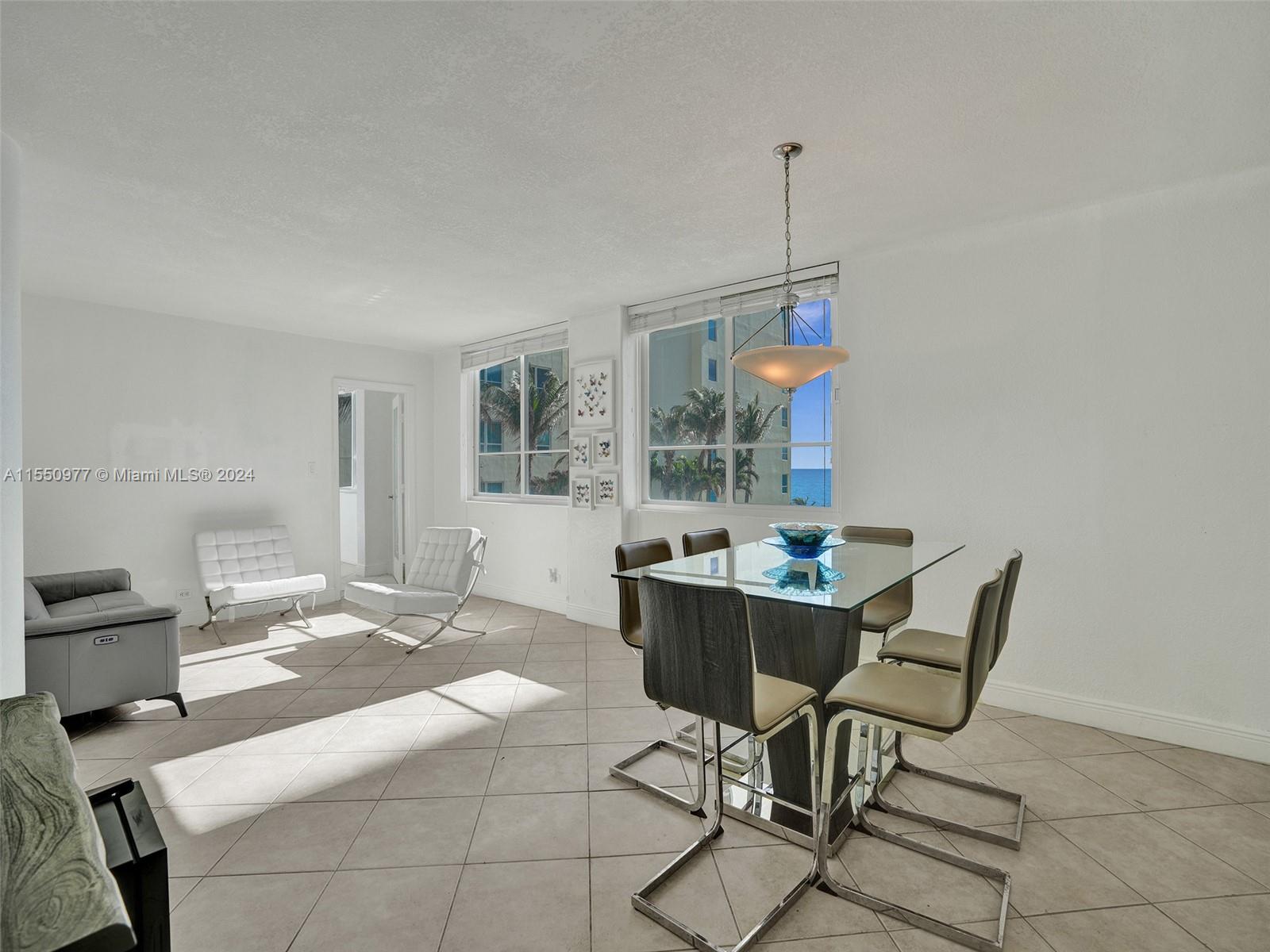 A bright dining and living area features tile floors, a glass table, and ocean views — 5005 Collins Ave # 725, Miami Beach FL 33140, MIAMI BEACH, FL