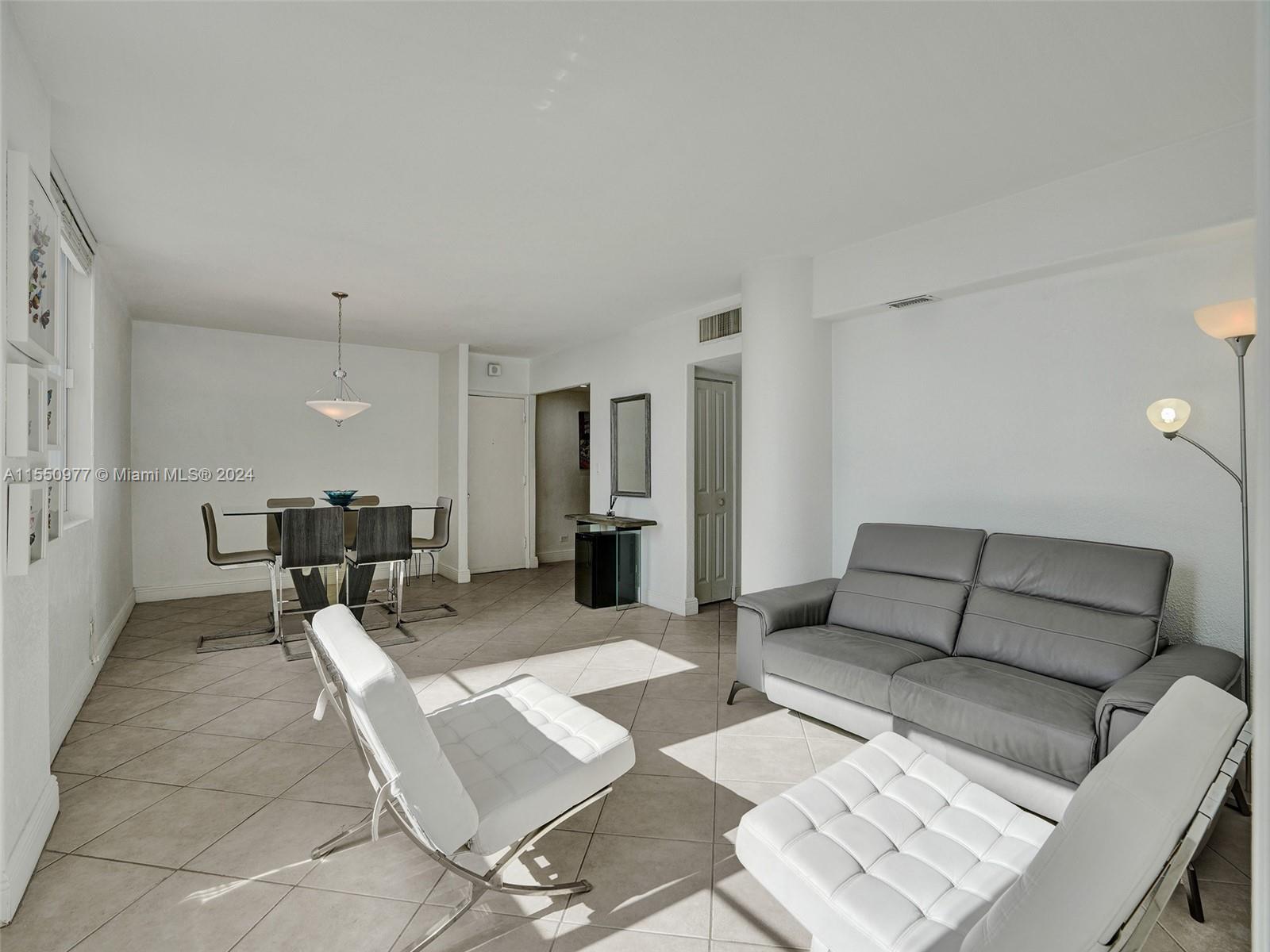 A living and dining area features white walls, tile floors, a gray sofa, and white chairs — 5005 Collins Ave # 725, Miami Beach FL 33140, MIAMI BEACH, FL