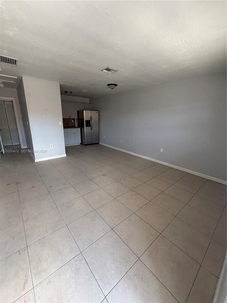 An open-concept room features light-colored tile flooring, gray walls, and a small kitchen area — 2924 NW 132nd Ter # 3, Opa-Locka FL 33054, OPA-LOCKA, FL