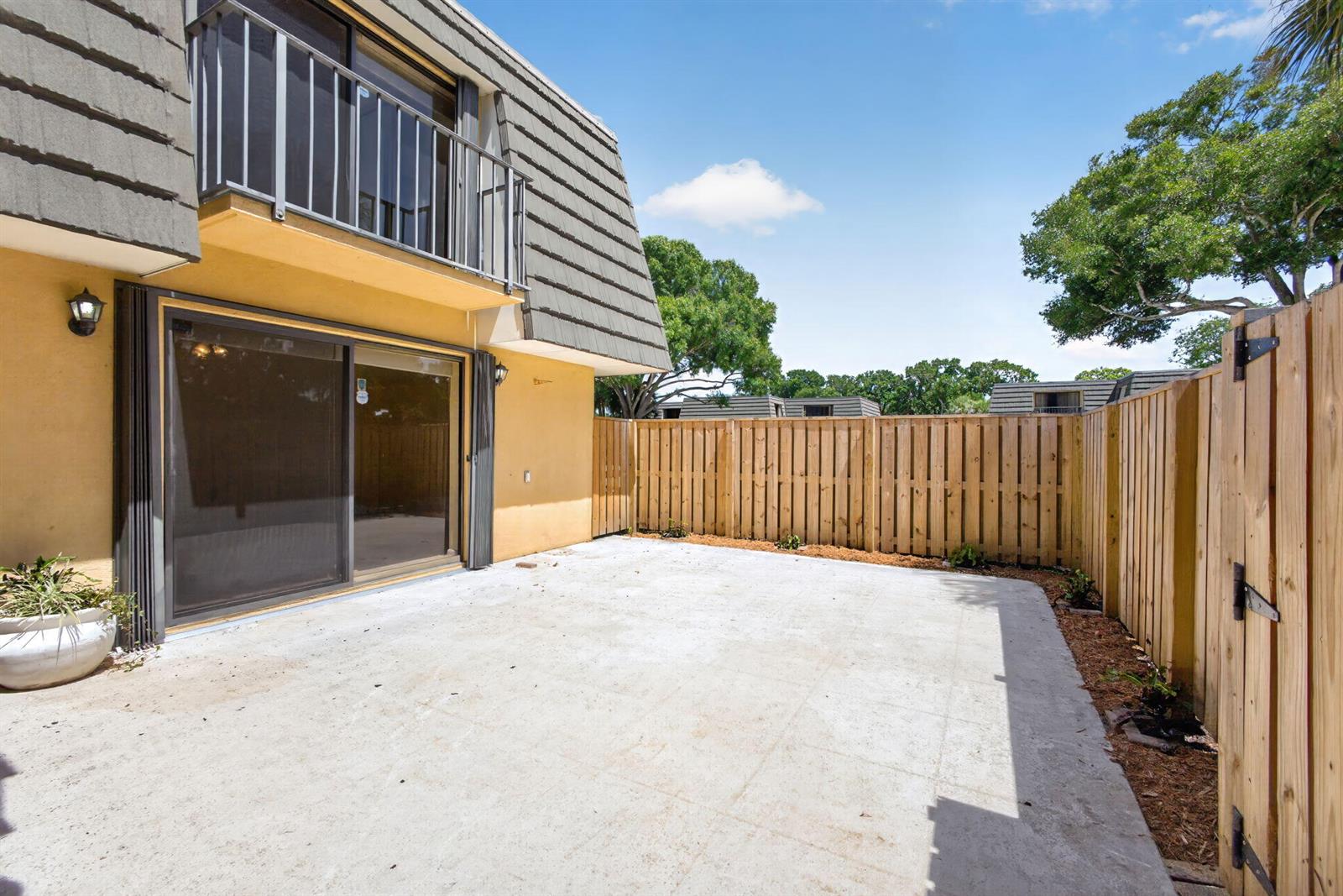 A concrete patio sits beside a two-story building with a wooden fence enclosure — 3501 35th Way, West Palm Beach FL 33407, WEST PALM BEACH, FL