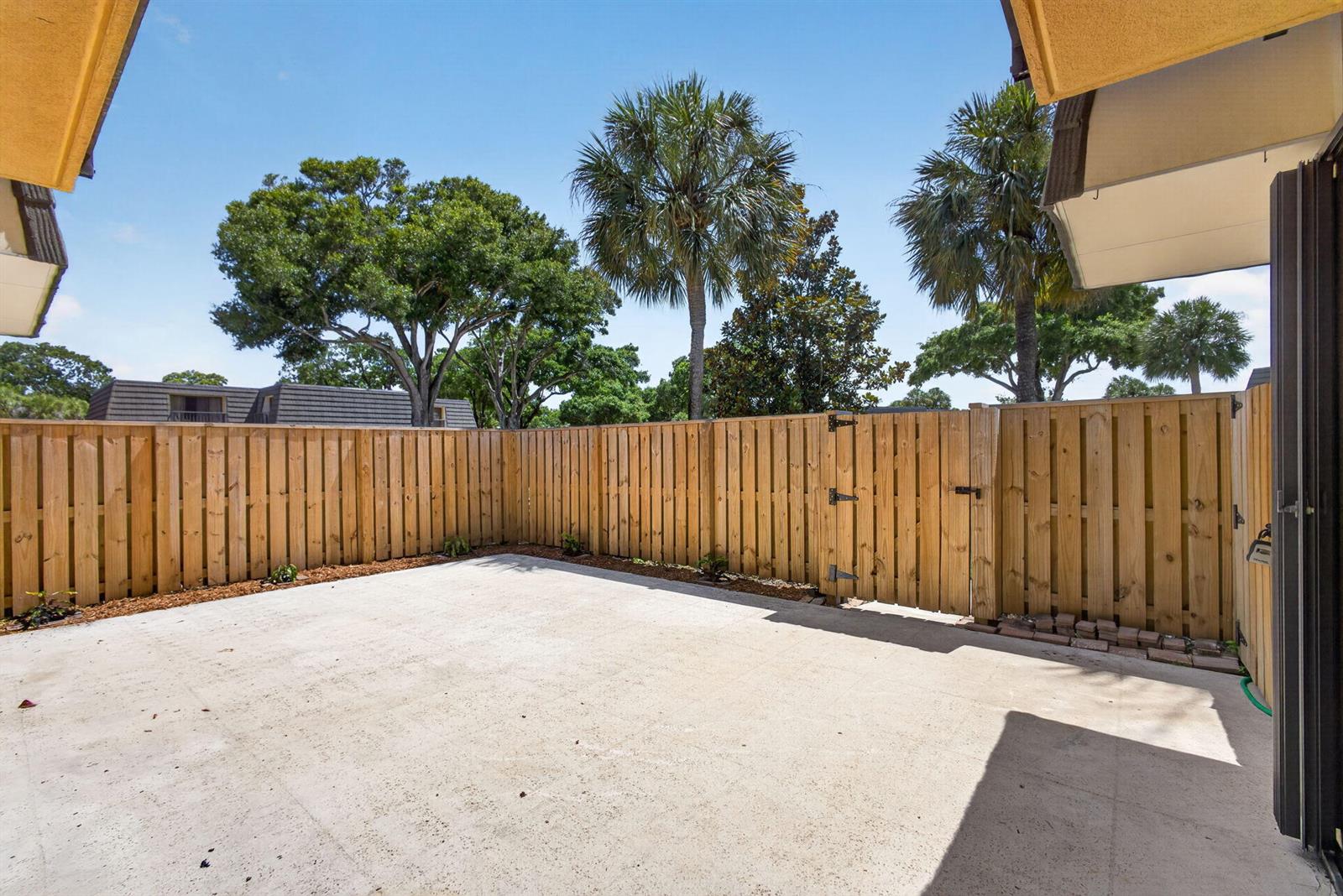 A concrete patio enclosed by a tall wooden privacy fence with a gate — 3501 35th Way, West Palm Beach FL 33407, WEST PALM BEACH, FL