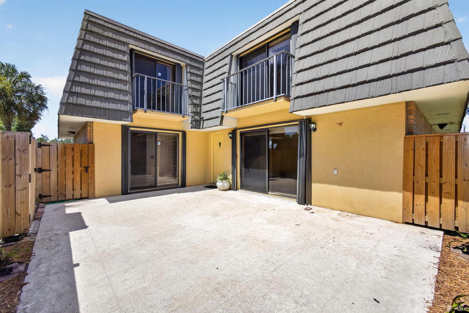 A concrete patio sits in front of a two-story yellow building with balconies — 3501 35th Way, West Palm Beach FL 33407, WEST PALM BEACH, FL