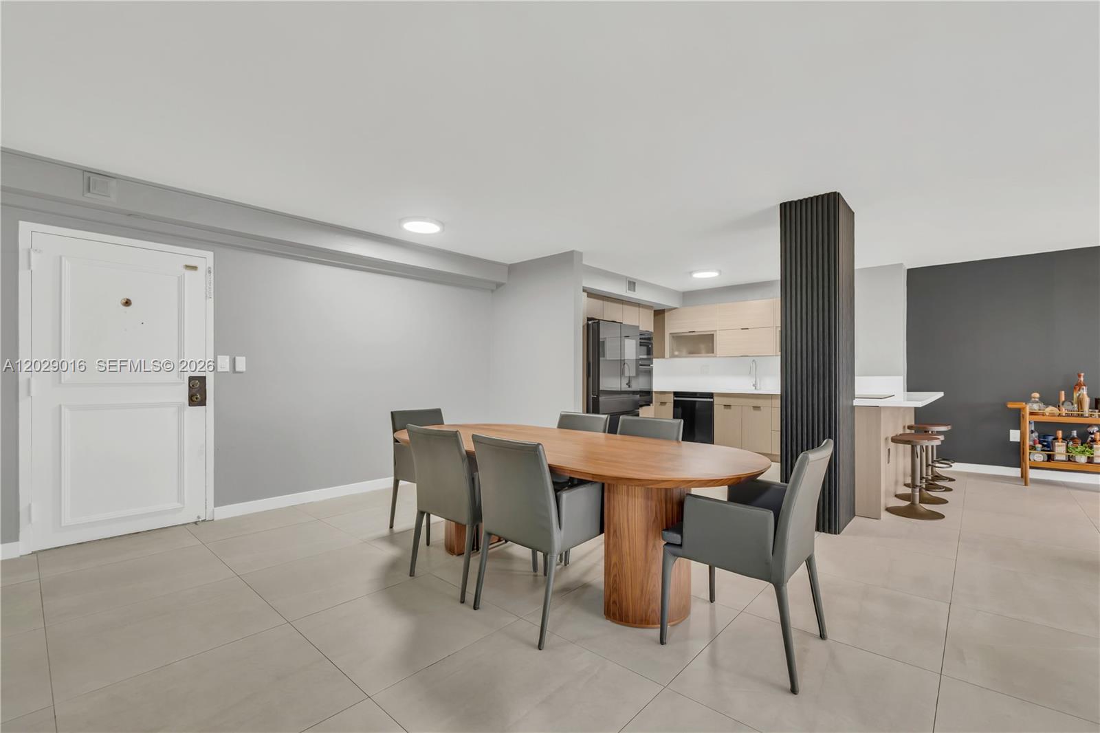 A dining area with a wooden table and grey chairs sits before an open kitchen — 1450 Brickell Bay Dr # 1815, Miami FL 33131, MIAMI, FL