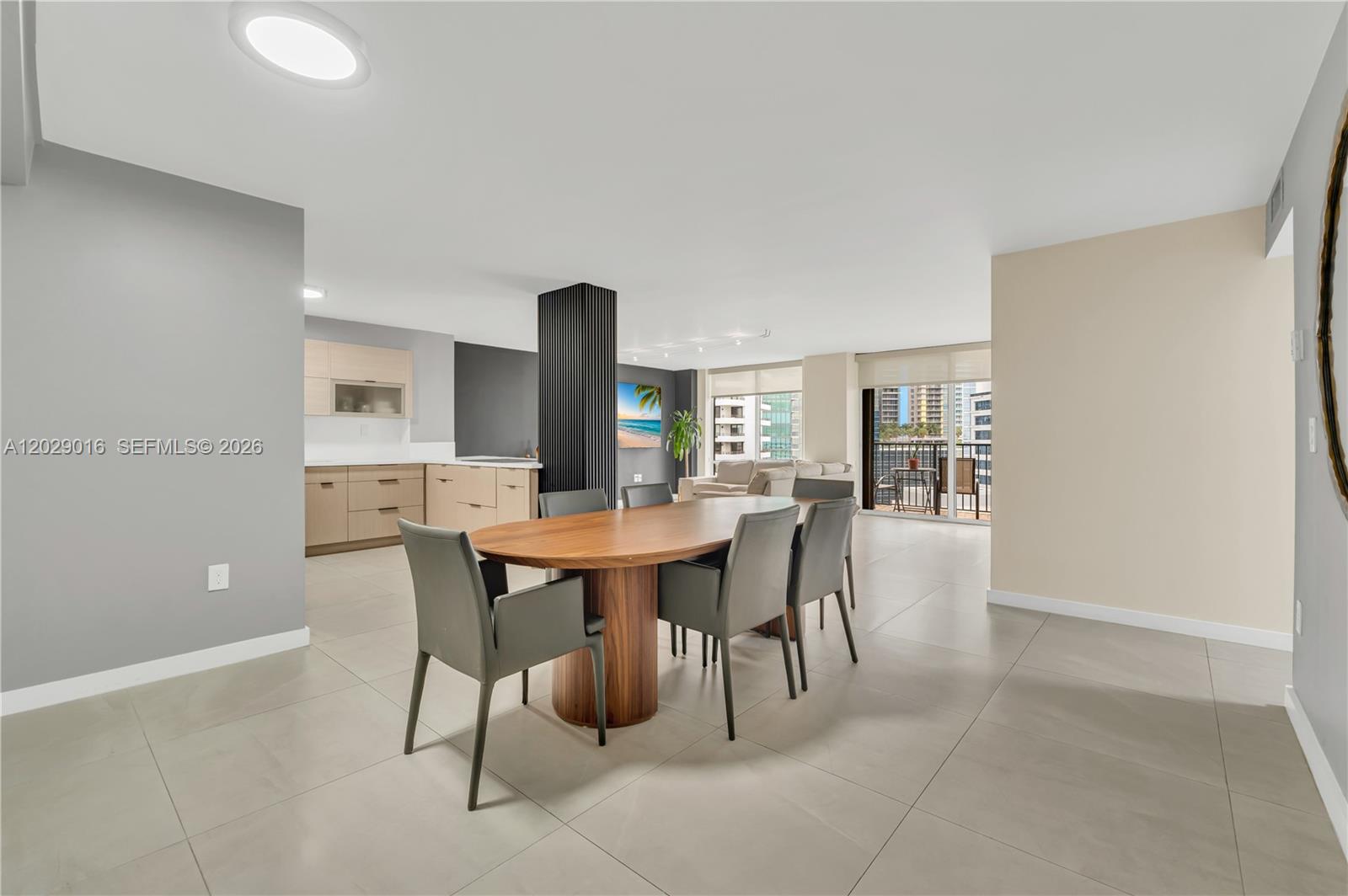 A dining area with a wooden table and grey chairs sits before an open kitchen — 1450 Brickell Bay Dr # 1815, Miami FL 33131, MIAMI, FL