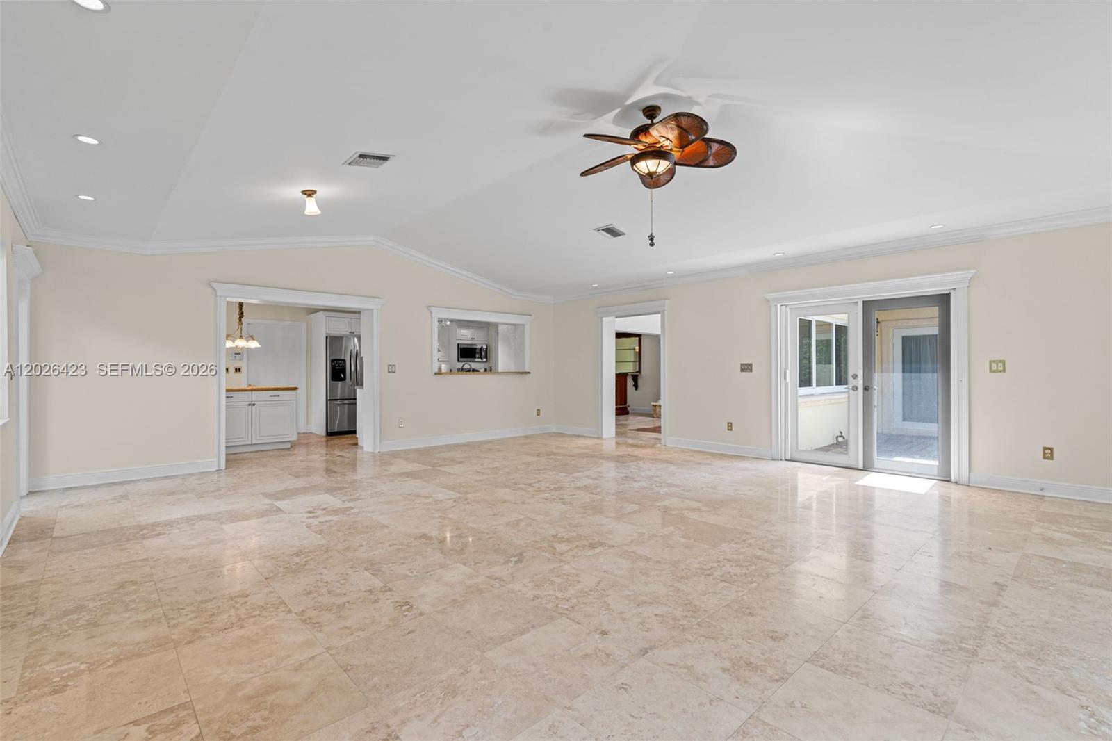 A spacious living room features light-colored tile flooring, a vaulted ceiling, and a ceiling fan — 730 NE 116th St, Biscayne Park FL 33161, BISCAYNE PARK, FL