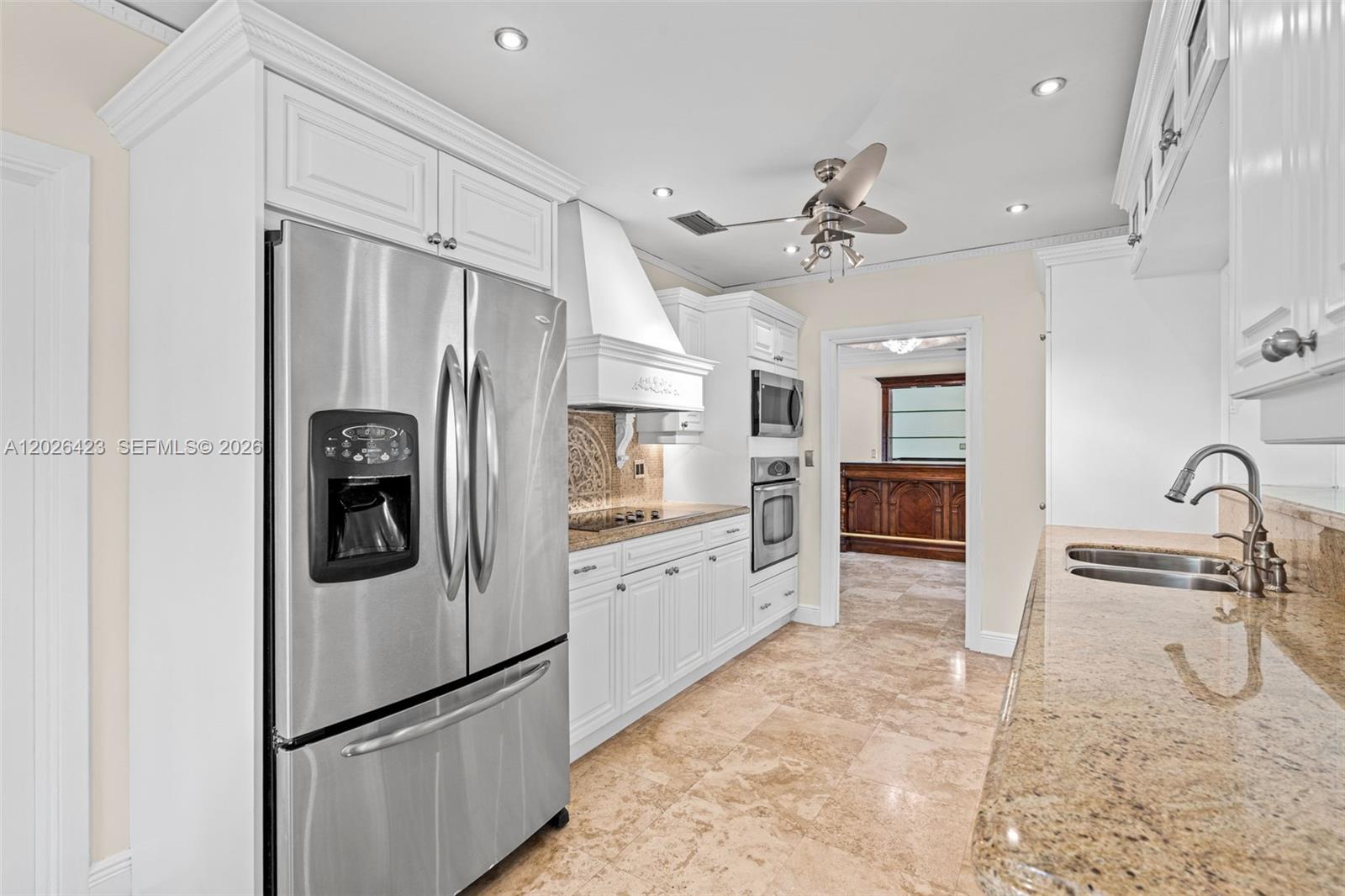 A kitchen features white cabinetry, stainless steel appliances, granite countertops, and light-colored tile flooring — 730 NE 116th St, Biscayne Park FL 33161, BISCAYNE PARK, FL