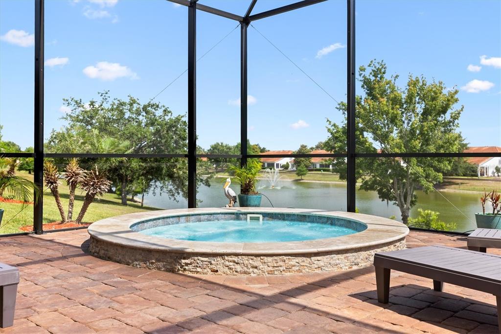 A circular spa with stone siding sits on a paved patio inside a screened enclosure — 5105 JAREDS LANDING WAY, OXFORD, FL