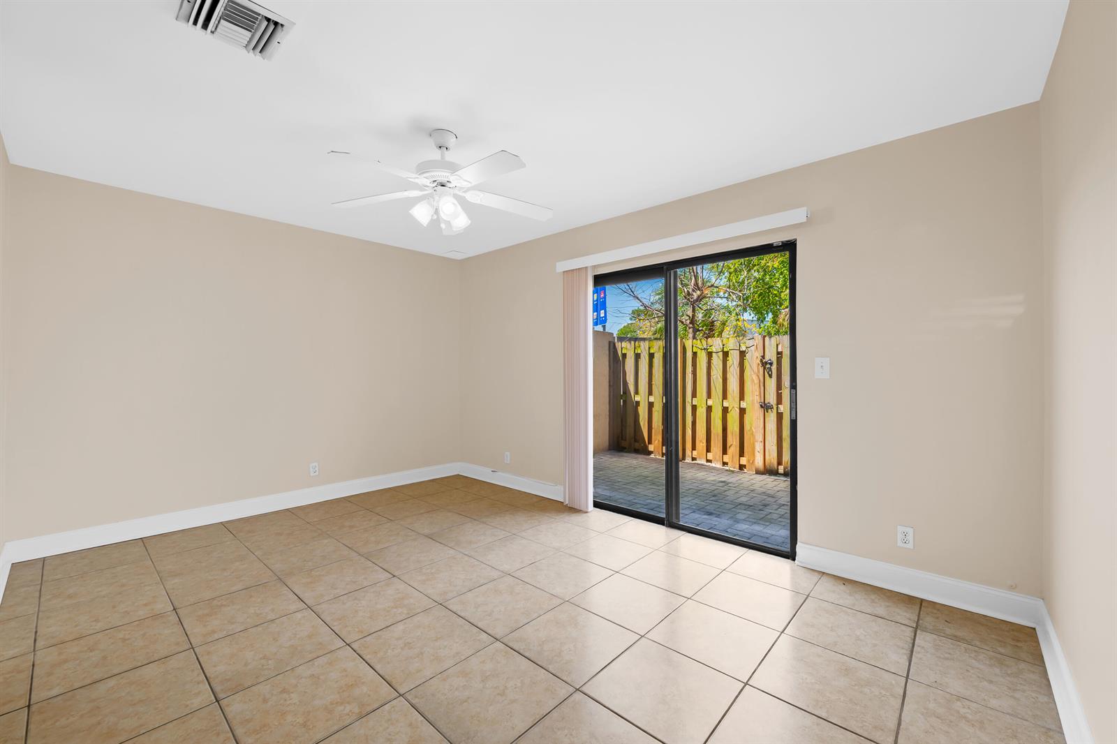 An empty room with beige walls, tile flooring, a ceiling fan, and sliding glass doors — 3281 E Golf Boulevard # 4, Pompano Beach FL 33064, POMPANO BEACH, FL