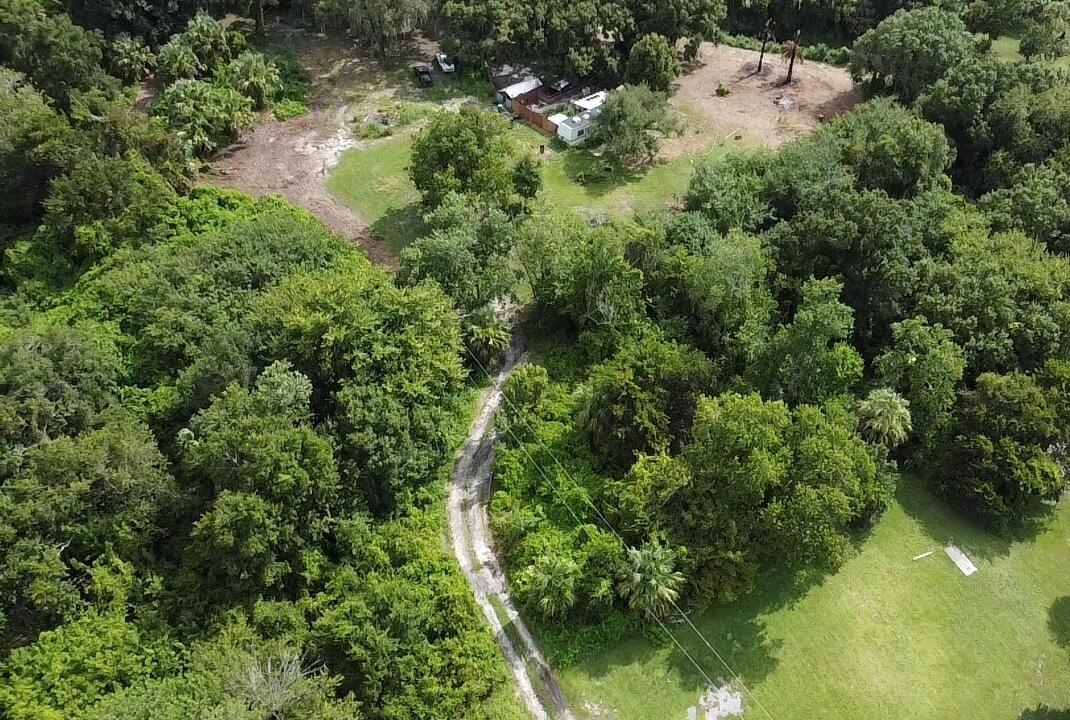 An aerial view shows a dirt driveway winding through a wooded lot toward a small house — 3255 NW 8th Street, Okeechobee FL 34972, OKEECHOBEE, FL