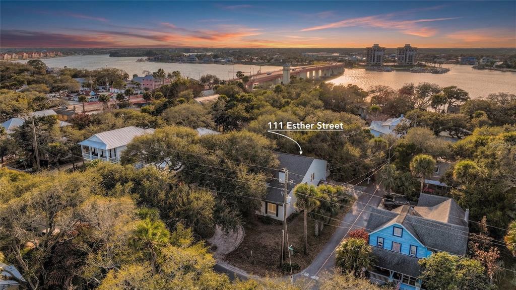 An aerial view shows a house nestled among trees near a bridge and waterfront — 111 ESTHER STREET, NEW SMYRNA BEACH, FL
