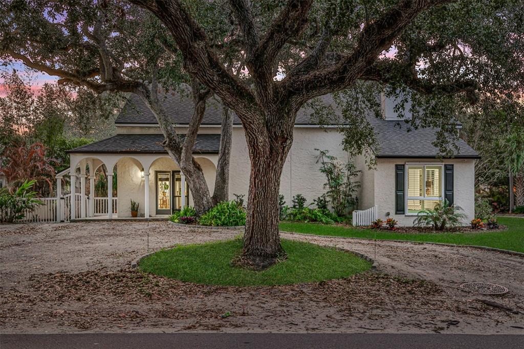 A cream-colored house with an arched porch and a large tree in the circular driveway — 111 ESTHER STREET, NEW SMYRNA BEACH, FL