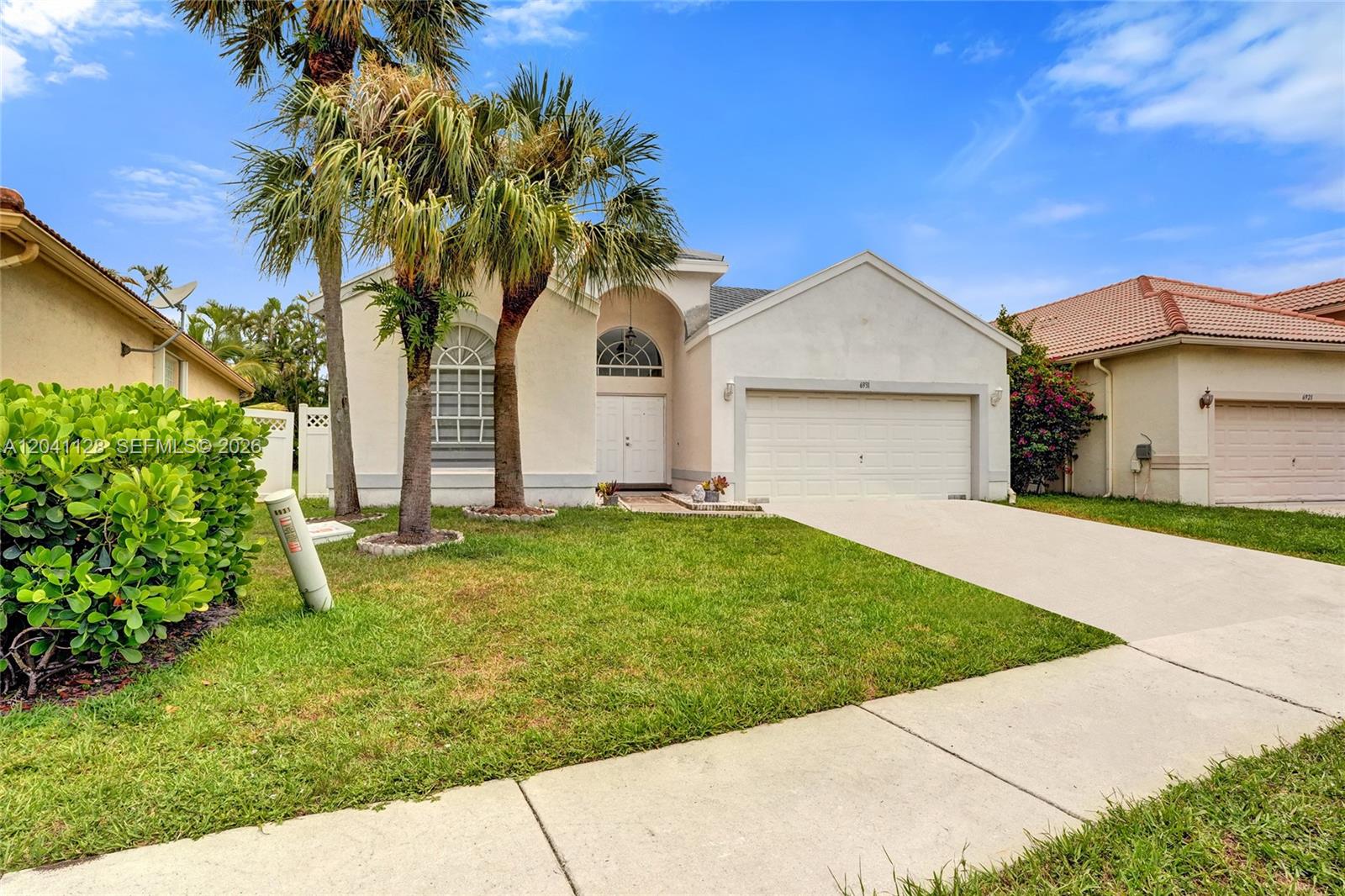 A single-story suburban house with a two-car garage, palm trees, and a manicured lawn — 6931 NW 34th St # 6931, Margate FL 33063, MARGATE, FL
