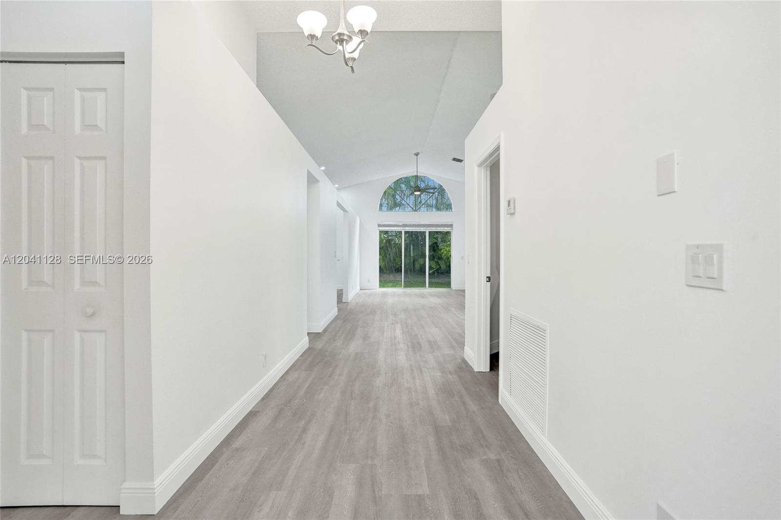 A bright hallway with light wood-look flooring leads toward a living area with arched windows — 6931 NW 34th St # 6931, Margate FL 33063, MARGATE, FL