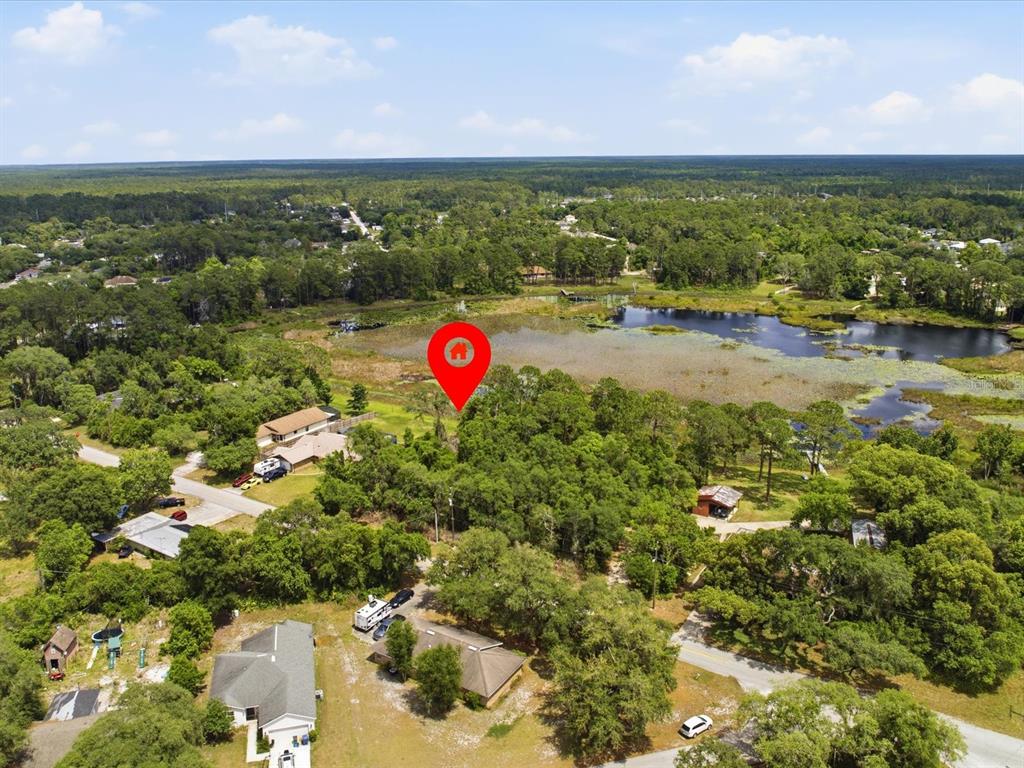 An aerial view shows a wooded lot with a red location pin near a lake — W LAKE DRIVE, DELAND, FL