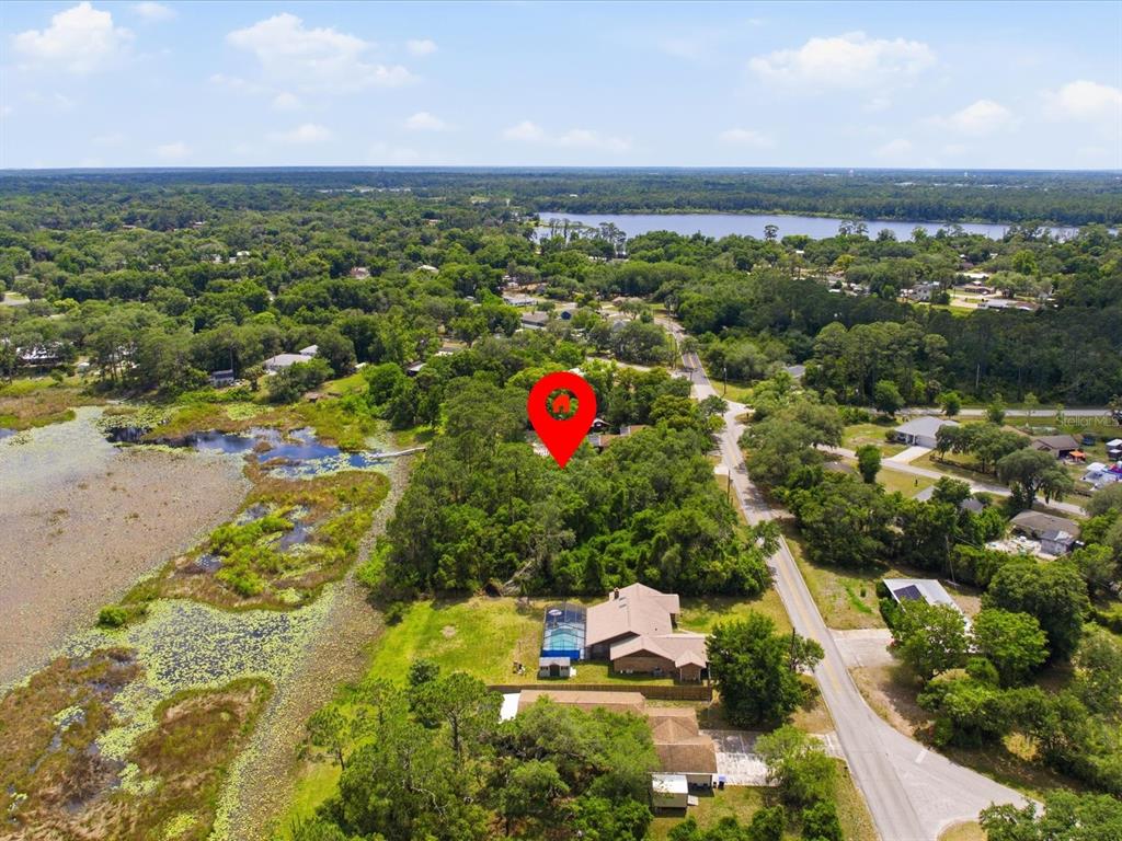 An aerial view shows a wooded lot marked with a red pin near a lake — W LAKE DRIVE, DELAND, FL