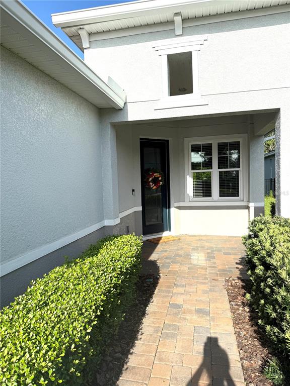 A paved walkway leads to the front entrance of a house with light-colored stucco walls — 173 OLD MOSS CIRCLE, DELAND, FL