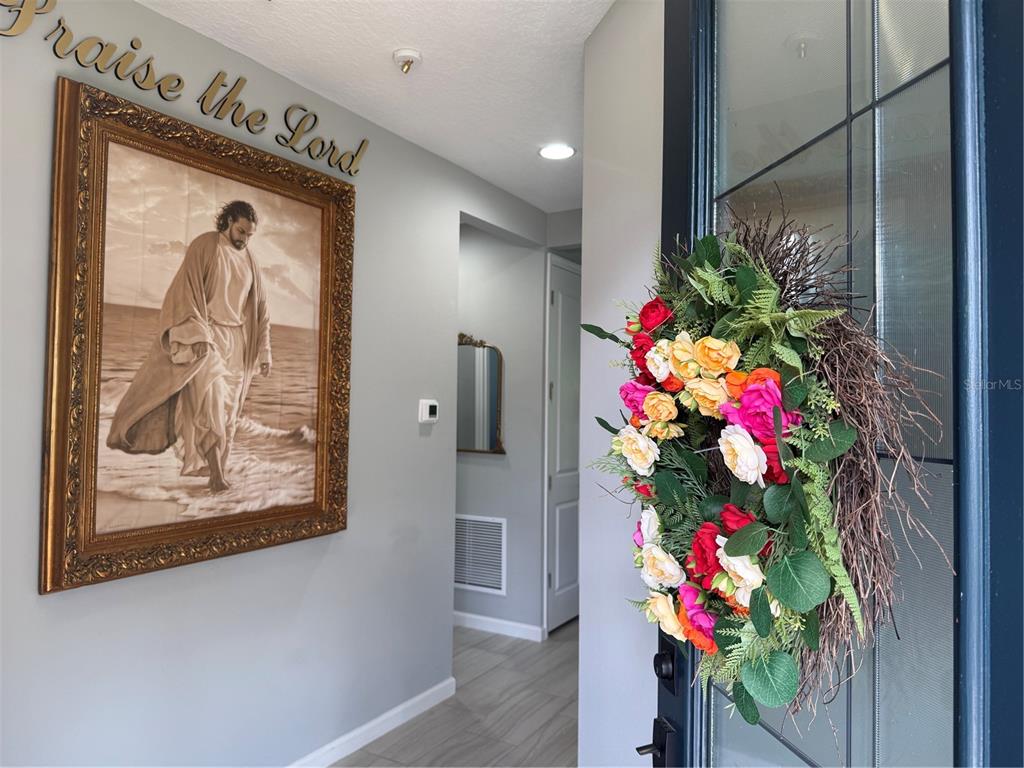 An entryway features a framed painting of Jesus, a floral wreath on the door, and tile flooring — 173 OLD MOSS CIRCLE, DELAND, FL