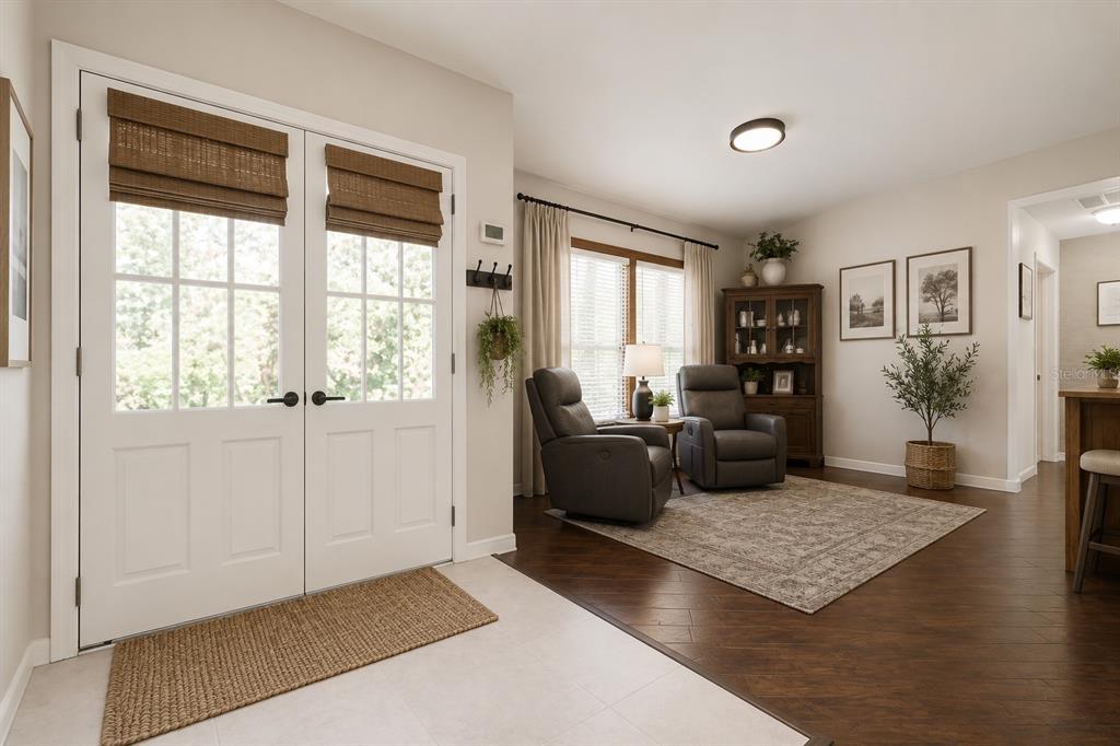 A bright entryway features double glass doors, tile flooring, and a seating area with recliners — 5105 KEYSVILLE AVENUE, SPRING HILL, FL