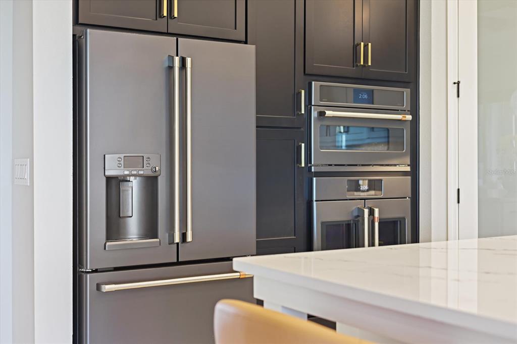 A modern kitchen features dark cabinetry, stainless steel appliances, and a white marble island — 13730 HEARTWOOD WAY, PARRISH, FL