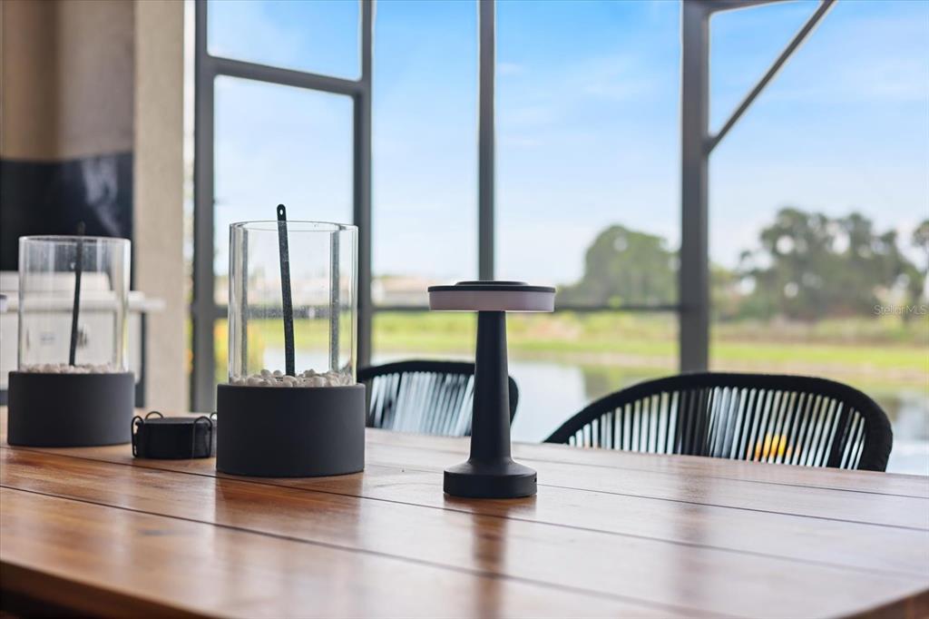A wooden table with decorative lanterns sits on a screened-in patio overlooking a pond — 13730 HEARTWOOD WAY, PARRISH, FL