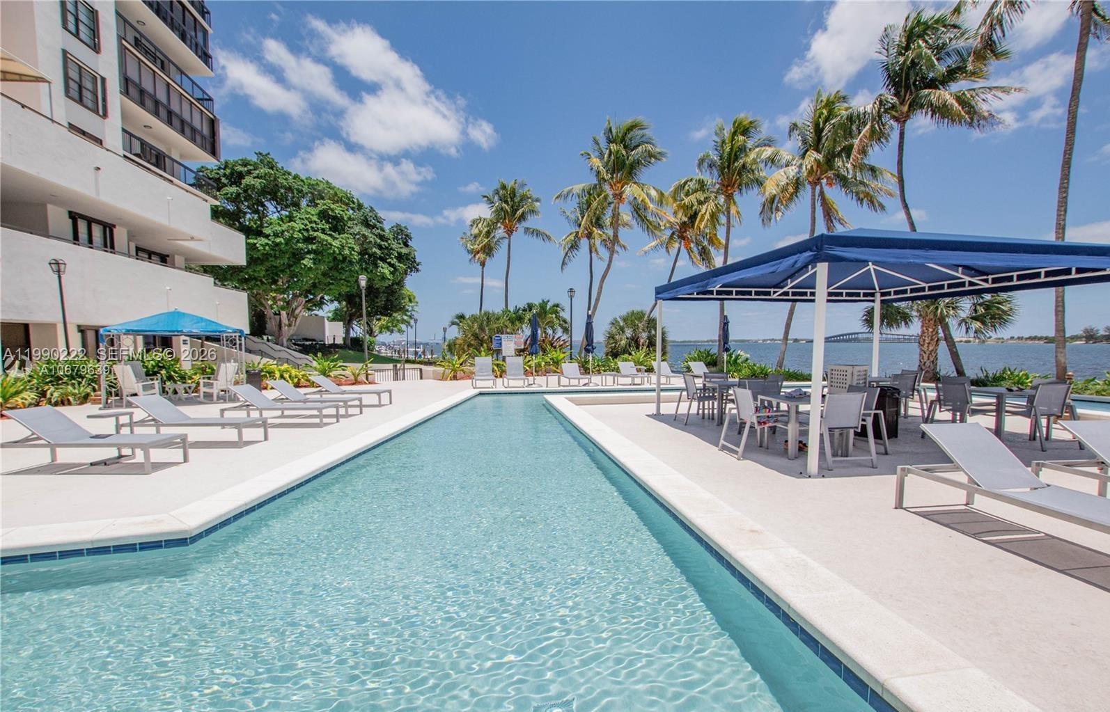 A swimming pool sits on a patio next to a building with palm trees nearby — 2333 Brickell Ave # 2607, Miami FL 33129, MIAMI, FL