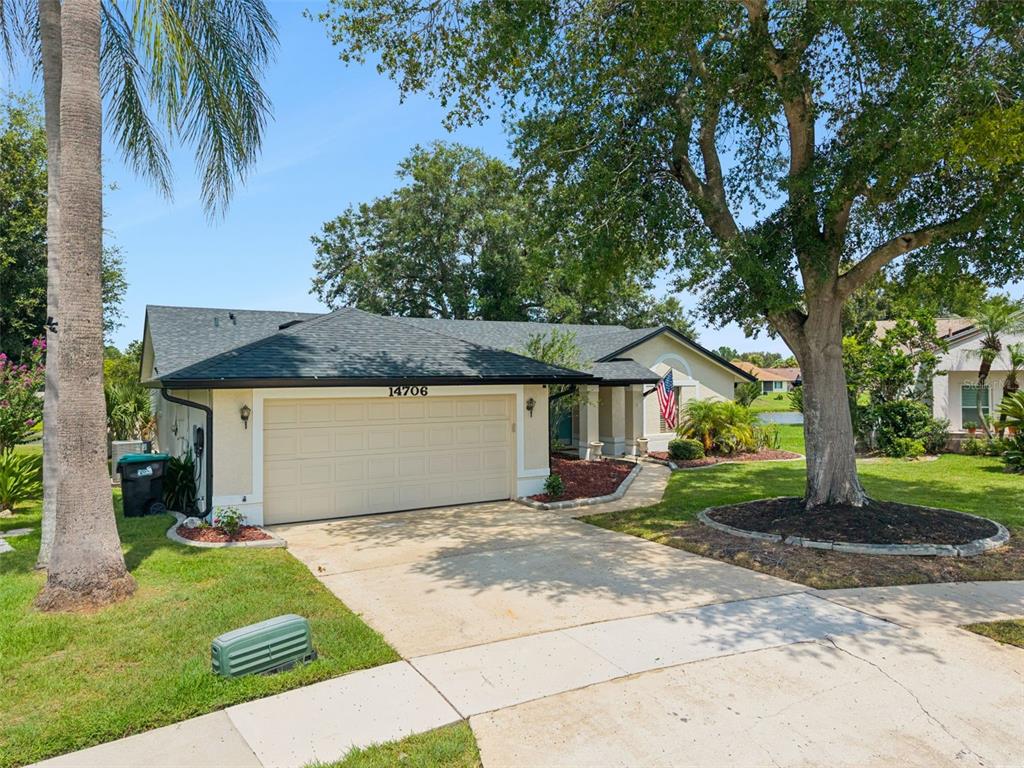 A single-story house with a beige garage, a concrete driveway, and a large front tree — 14706 EAGLE VIEW COURT, ORLANDO, FL