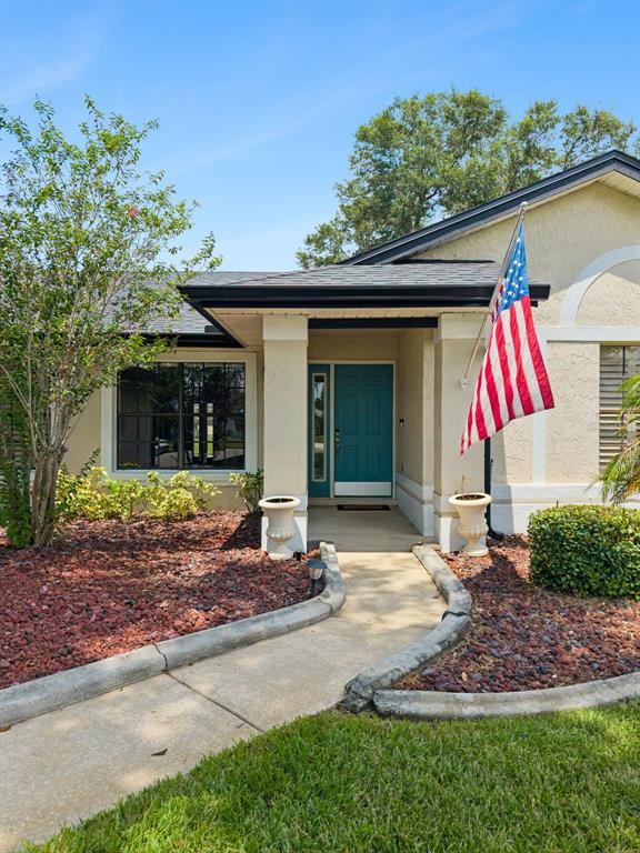 A single-story house features a teal front door, a walkway, and an American flag — 14706 EAGLE VIEW COURT, ORLANDO, FL