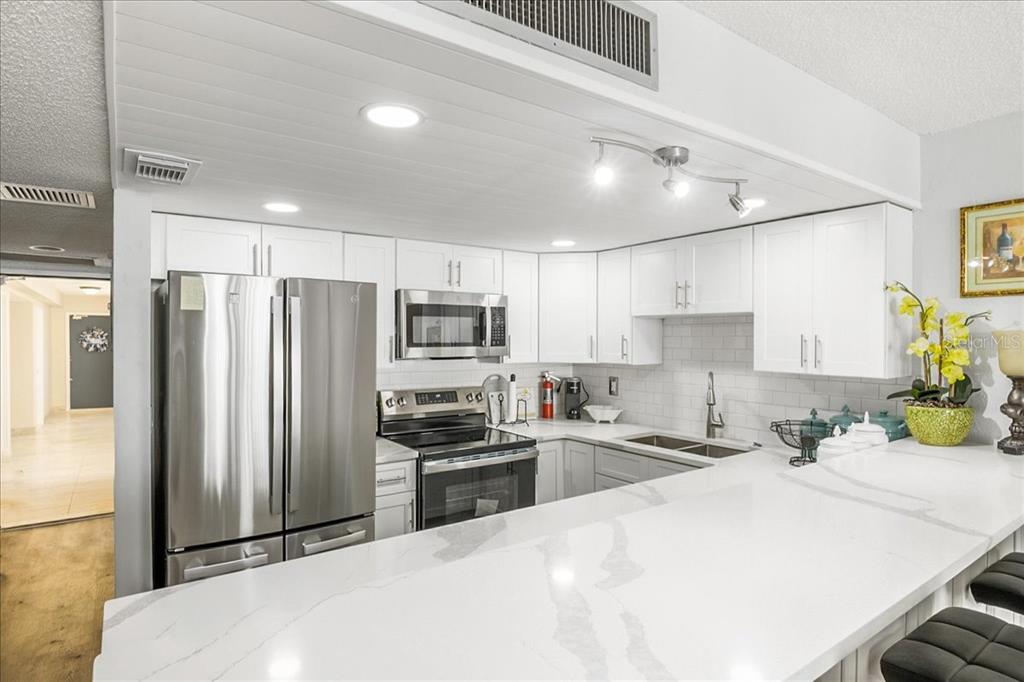 A modern kitchen features white cabinets, stainless steel appliances, and a white quartz countertop — 2947 S ATLANTIC AVENUE UNIT 506, DAYTONA BEACH, FL