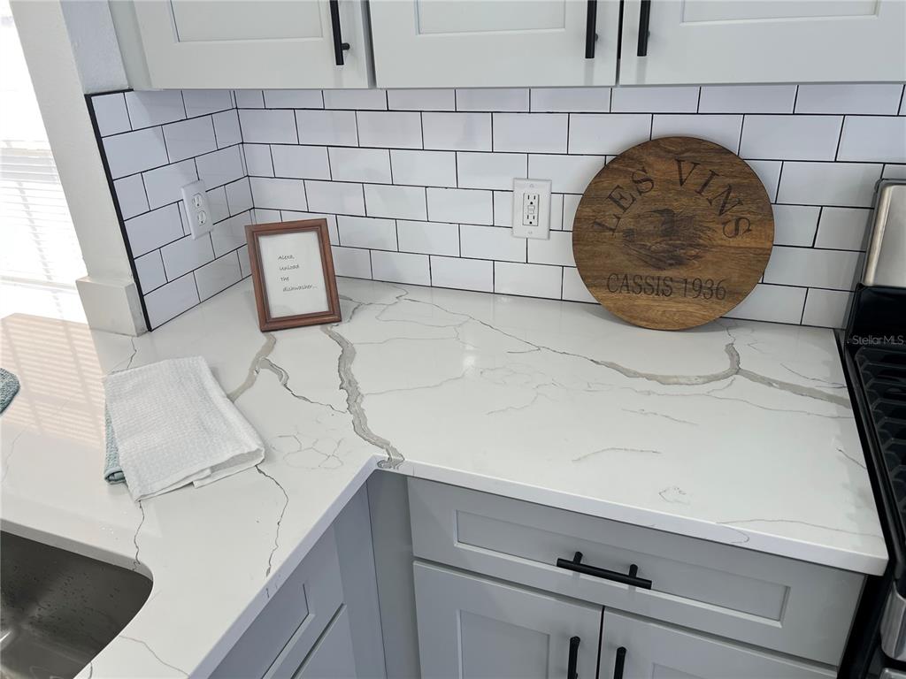 A kitchen features white subway tile backsplash, grey cabinets, and white quartz countertops with veining — 207 HIGH RIDGE DRIVE, DAVENPORT, FL